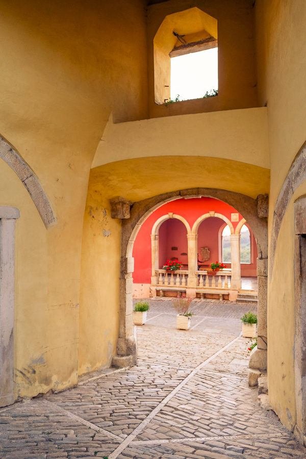 A vibrant archway leading to a beautiful courtyard in a yellow building invites visitors to explore Istria.