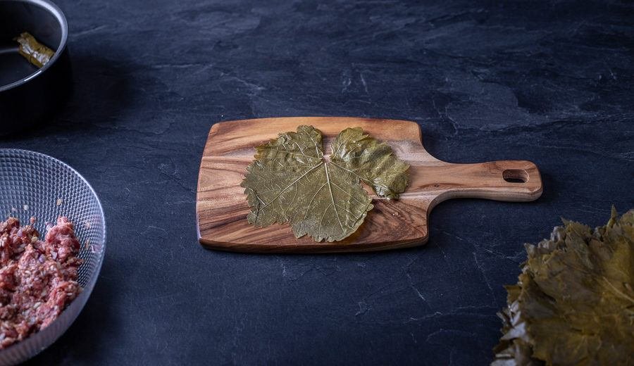 A tasty Bulgarian dish prepared on a wooden cutting board, garnished with fresh leaves.