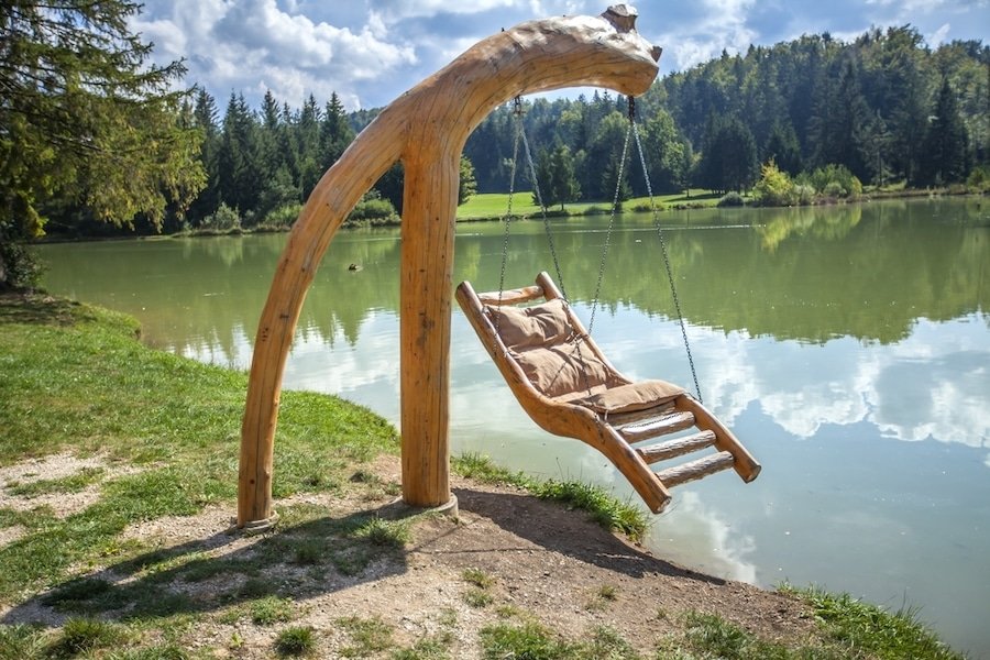Lakes In Slovenia - Wooden swing over Lake Bloke in Nova Vas, Slovenia on a sunny day
