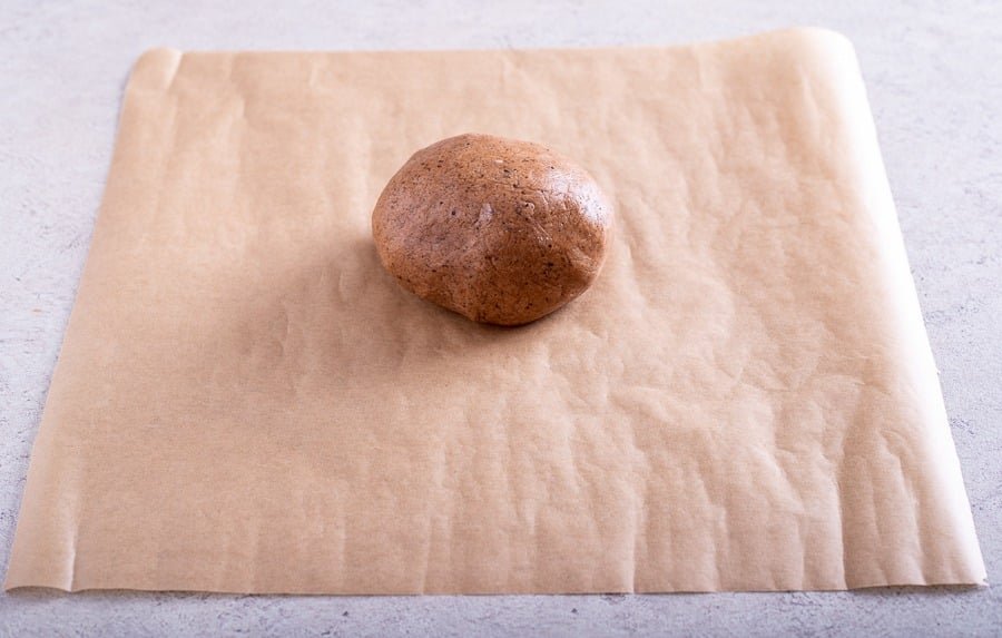A potato on a piece of brown paper on a table, with Croatian Paprenjaci.