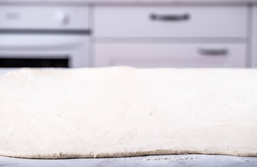 A large piece of dough on a counter top, ideal for making Croatian croissants or salenjaci.