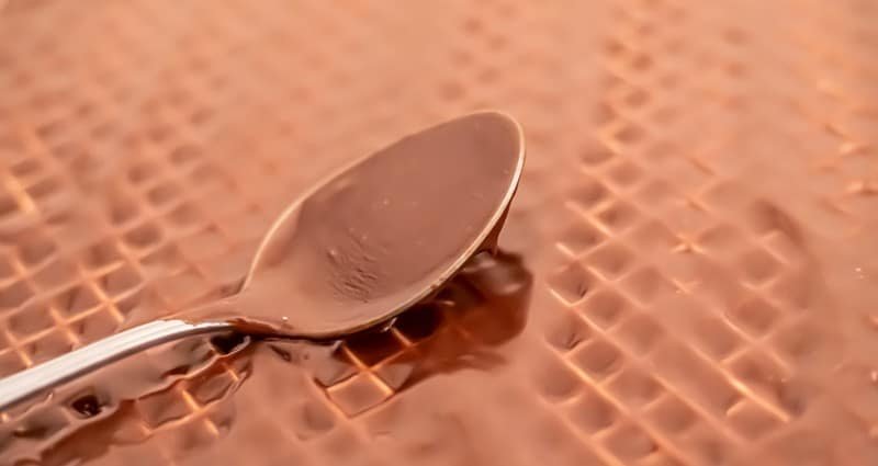 A spoon is sitting on top of a copper surface, making it an ideal place for Oblatne with Čokoladnom Karamel Kremom.