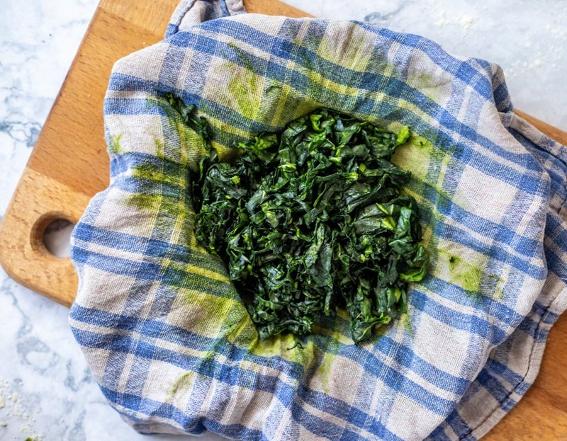 Rudarska Greblica recipe featuring spinach served on a blue and white checkered cloth on a cutting board.
