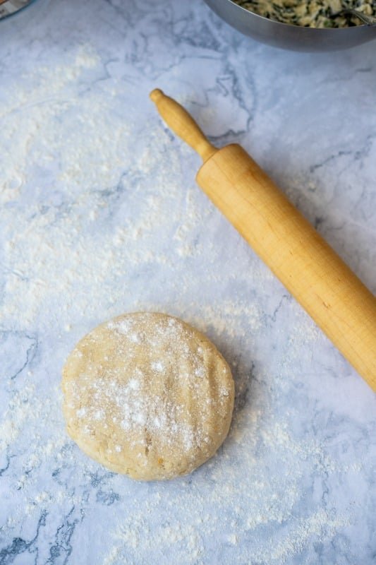 A Rudarska Greblica, a traditional Croatian recipe, consisting of a bowl of flour and a rolling pin on a marble countertop.