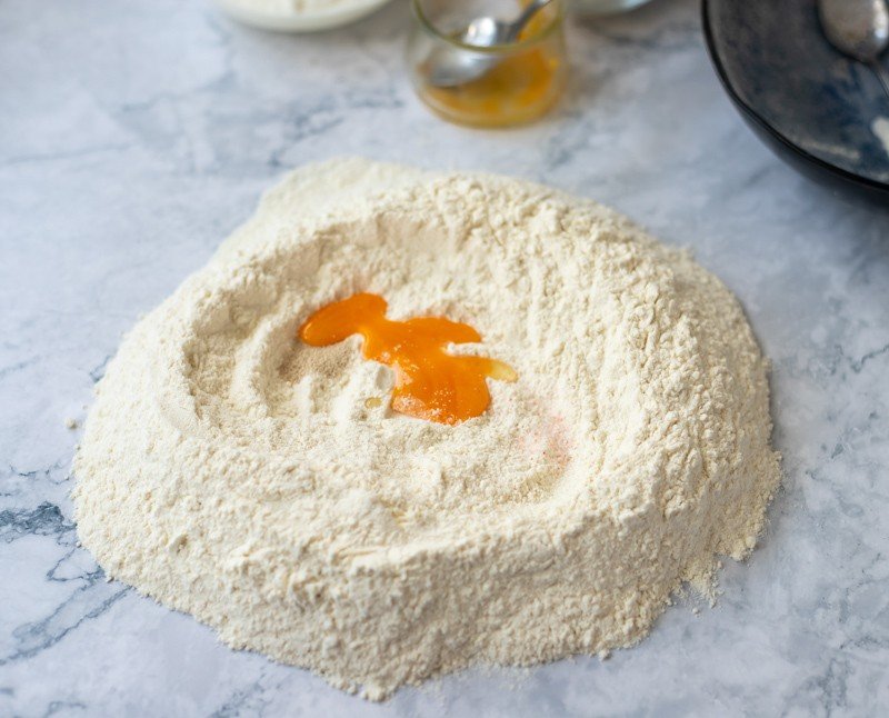 A bowl of flour and an egg, the essential ingredients for preparing a traditional Croatian recipe called Rudarska Greblica, are delicately arranged on a sleek marble countertop. The combination