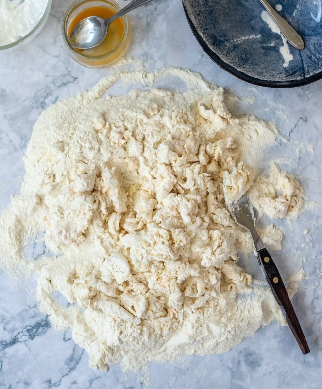 A bowl of flour and other ingredients for a Croatian recipe on a marble table.
