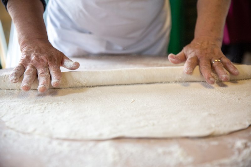 A Private woman is kneading Vegan-Friendly dough on a table.