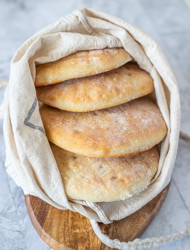 Four pita breads in a bag on a table.