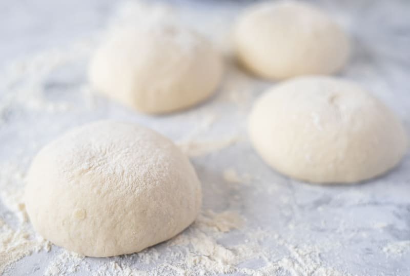 Three balls of somun dough on a marble table.