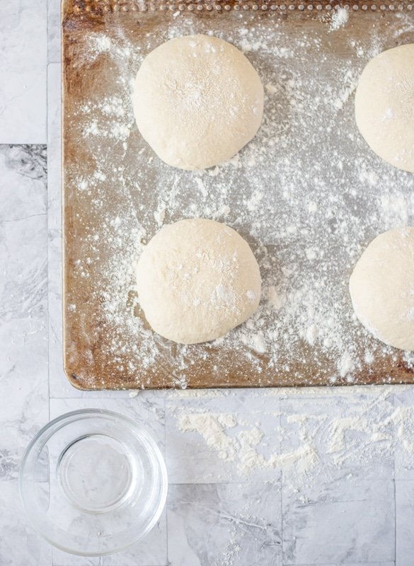 Four dough balls on a bread baking sheet.