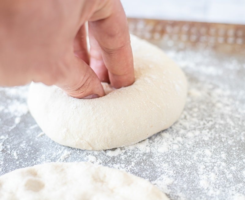 A hand is putting flour on a dough to make the best bread, Ćevapi.