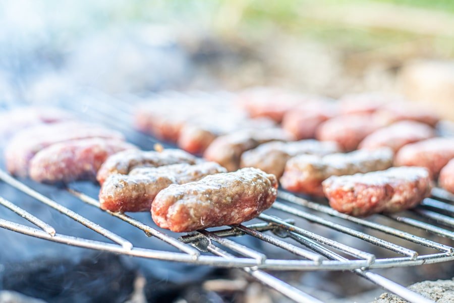 Skinless sausages, known as Sarajevski Ćevapi, are being cooked on a grill.