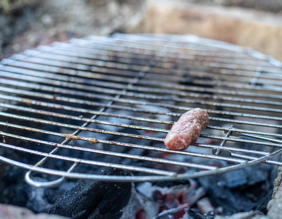 A Sarajevski Ćevapi sausage being cooked on a grill grate.