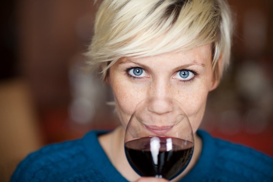 Blond Woman Drinking Red Wine In Restaurant