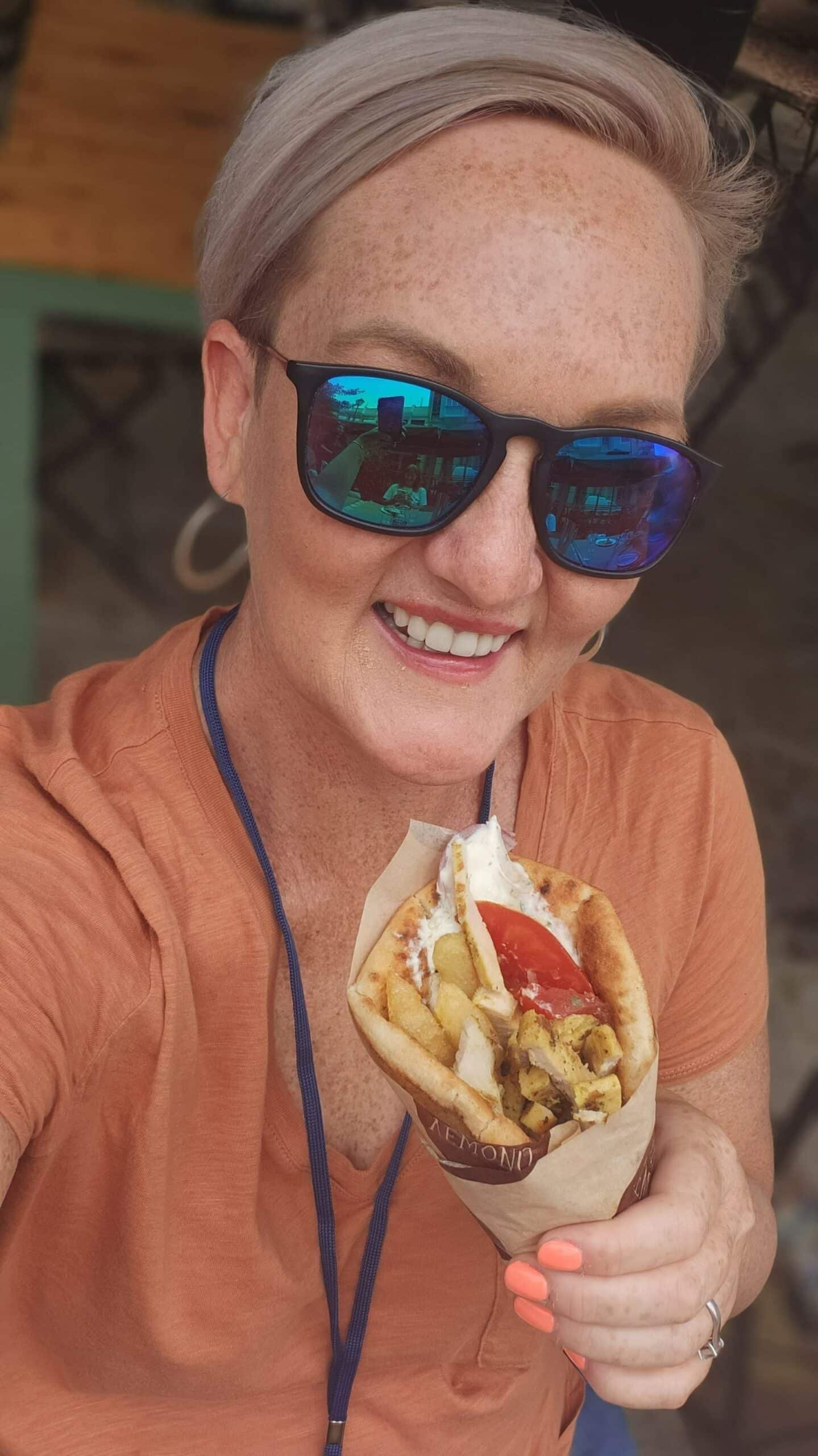 A woman wearing sunglasses enjoying a delicious hot dog in Nin.