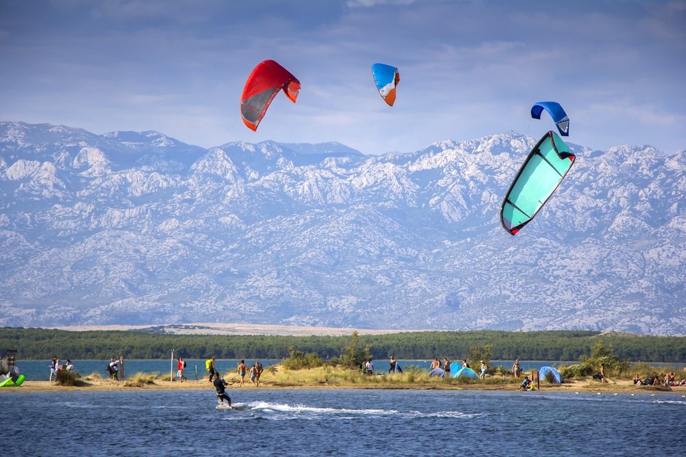 A group of people enjoying kitesurfing in the water, one of the thrilling activities to do in Nin.