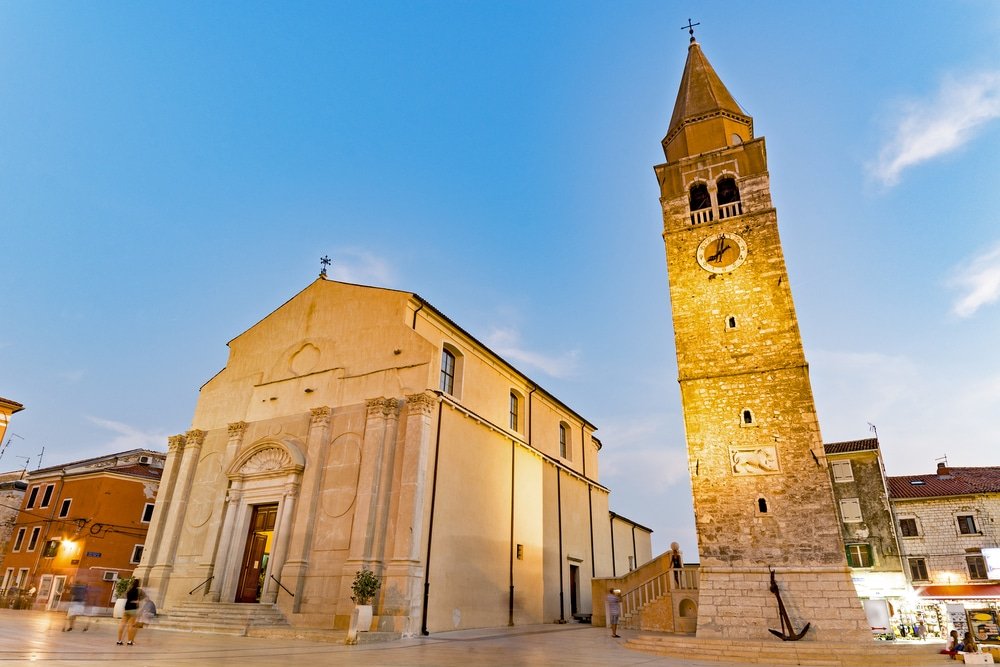Umag town in Croatia, main square with church and tower (campanile) at dusk