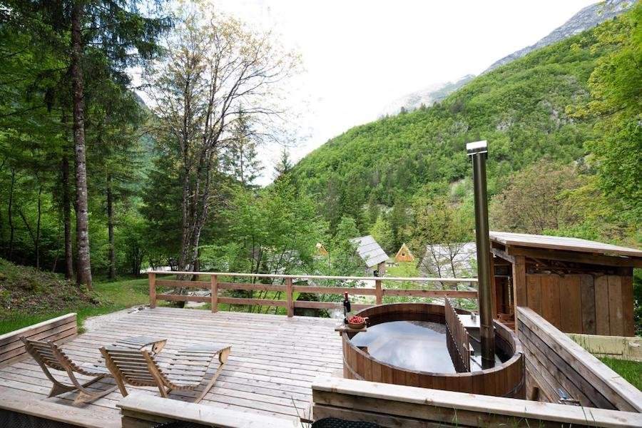 A wooden deck with a hot tub in the mountains, perfect for glamping in Slovenia.
