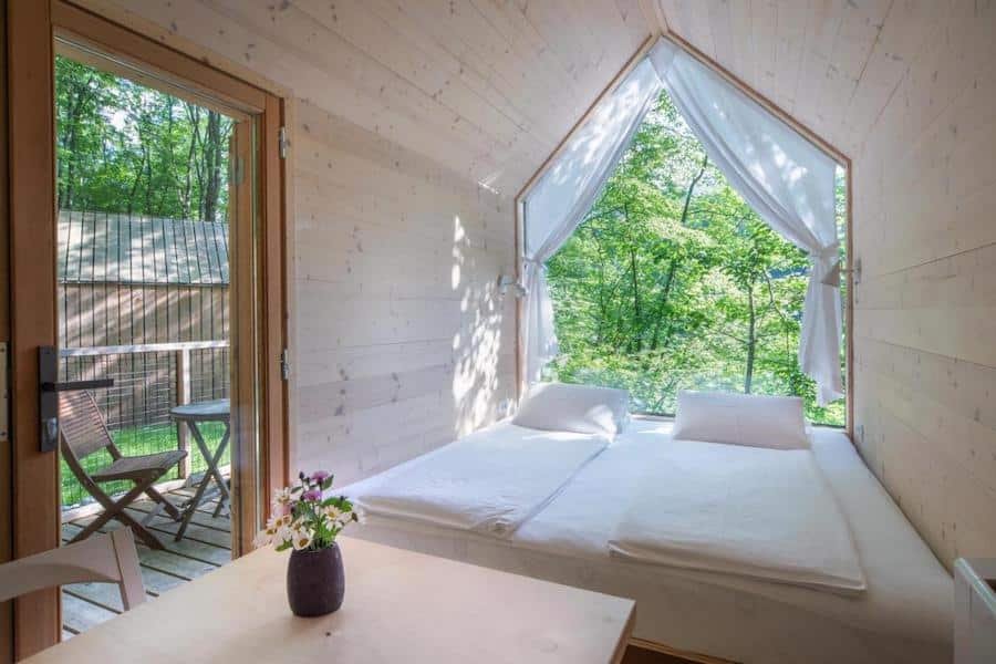 A wooden glamping cabin in Slovenia with a bed and a window.