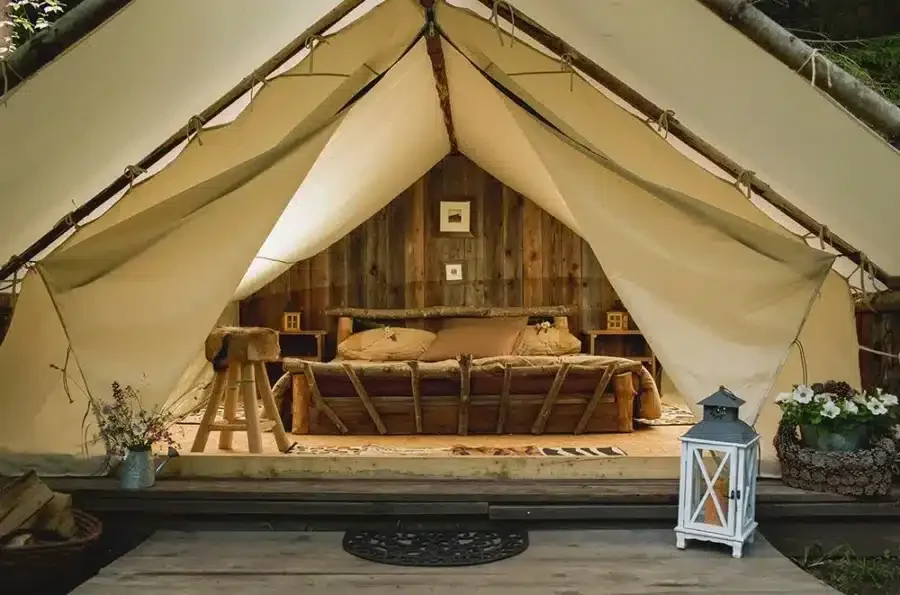 A glamping tent in the woods of Slovenia with a bed inside.