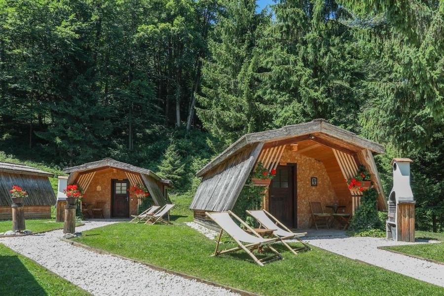 A group of wooden cabins in a wooded area, perfect for glamping in Slovenia.