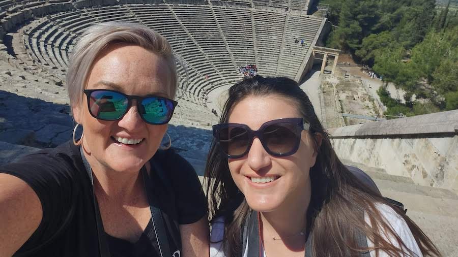 Two women taking a selfie in front of an ancient theater in Nafplio, Greece.