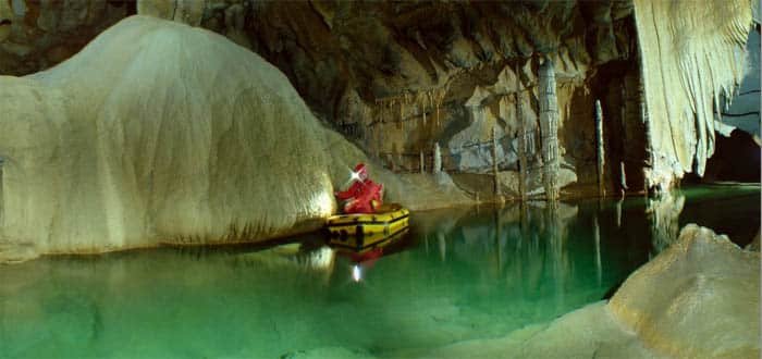 A person in a red outfit paddling a small yellow raft in Slovenia's underground caves with clear water Krizna jama cave