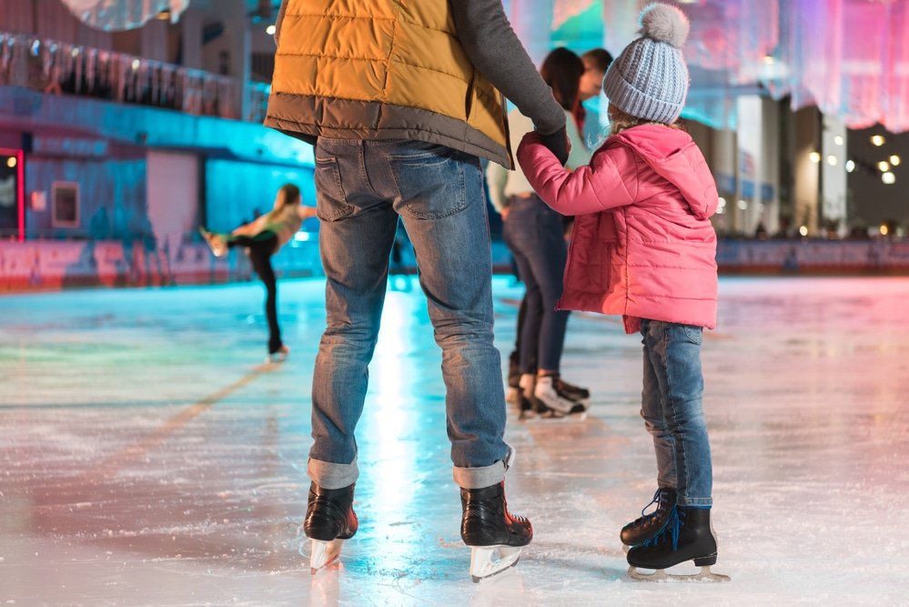 A man and a child enjoying winter ice skating at an ice rink in Bulgaria.