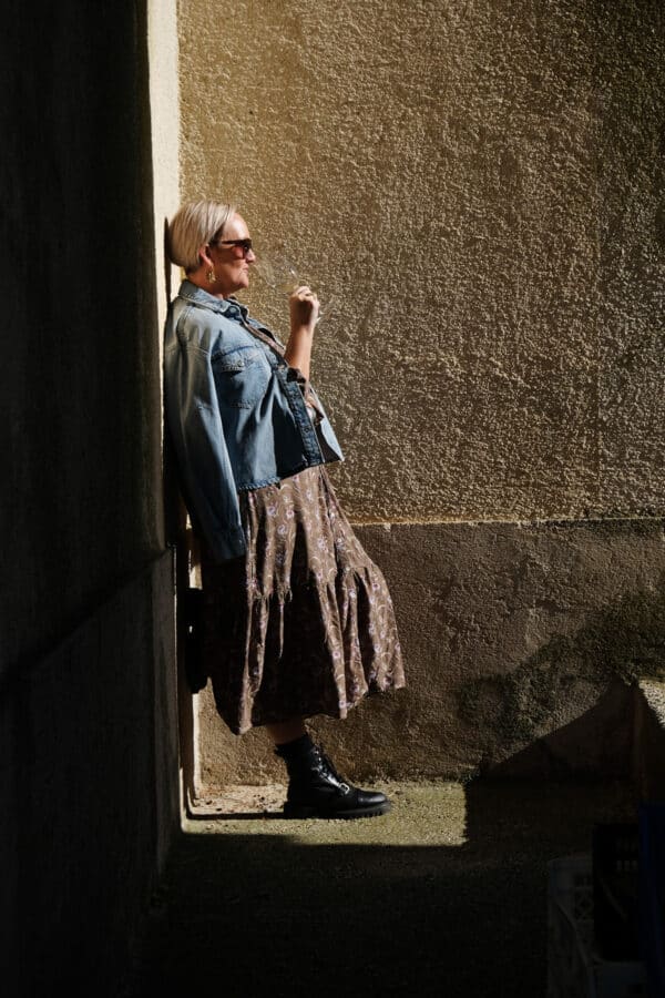 Sj leaning against a wall with a glass of wine