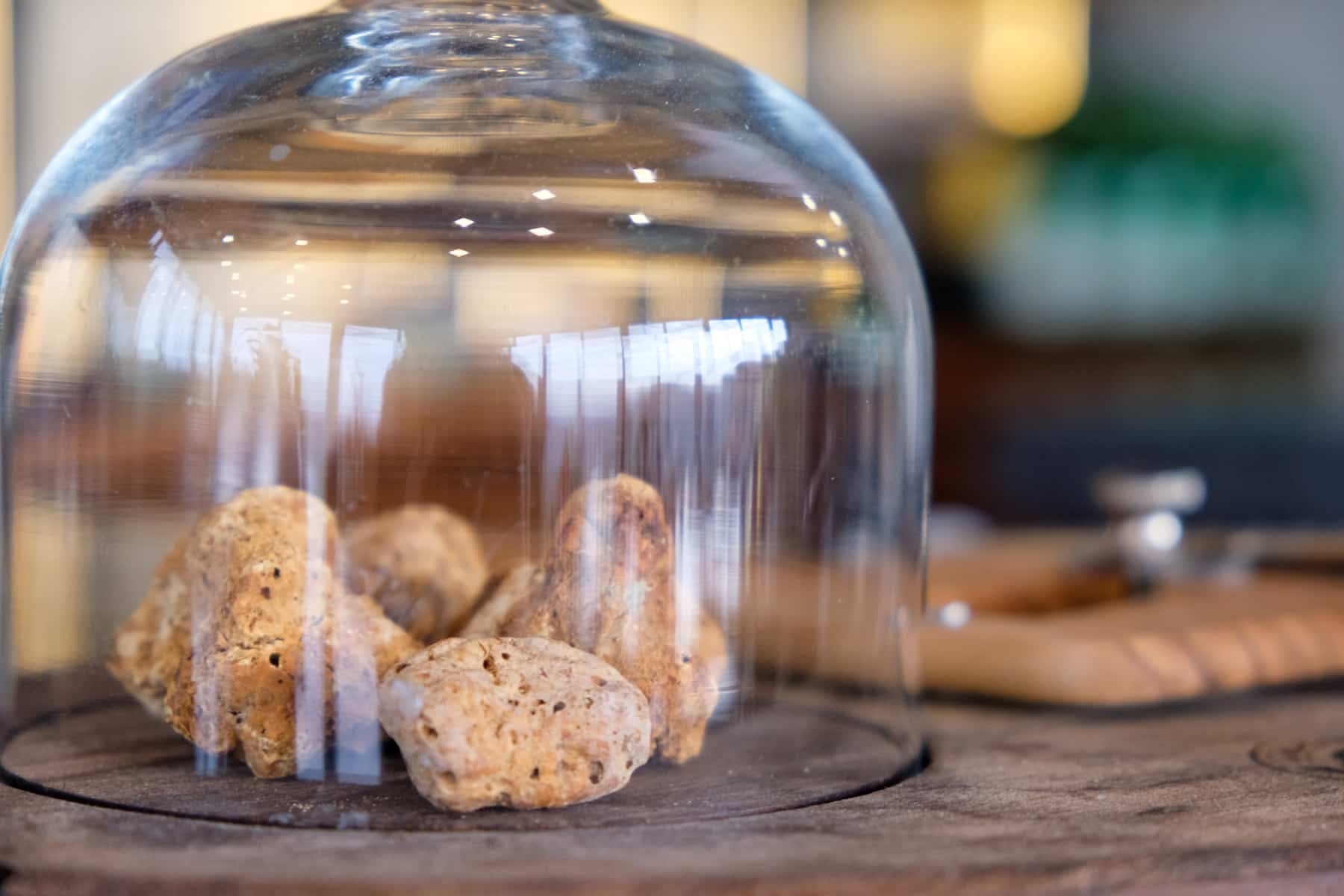 Truffles from Istria under a glass dome on a wooden table.