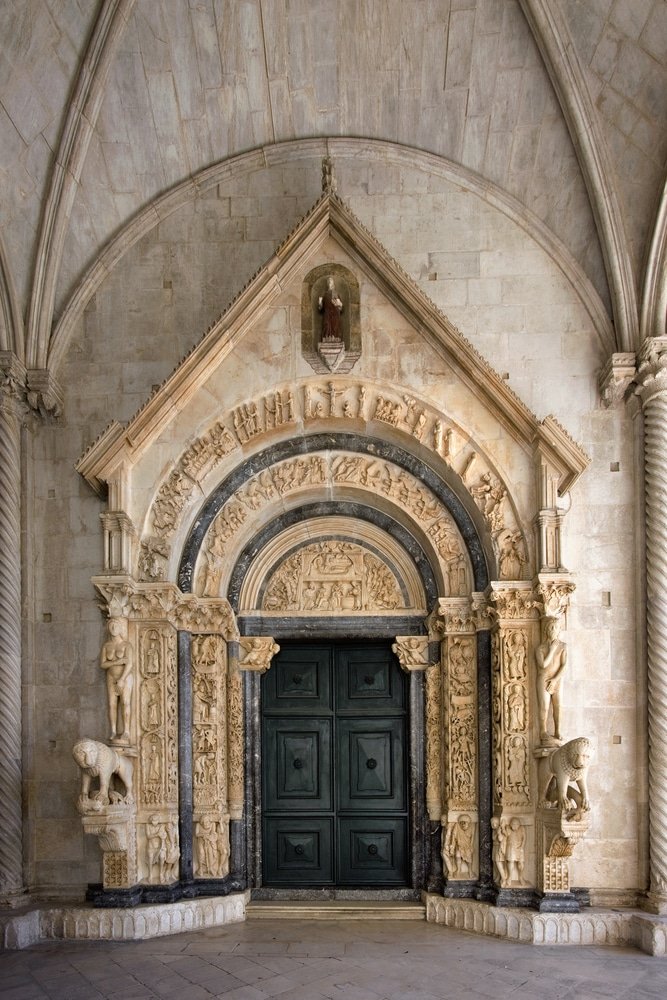 An ornate door of the The Cathedral Of St. Lawrence in Trogir, Croatia with a green door. Radovan portal is the main portal of the cathedral of St Lawrence done by Radovan in 1240. Trogir, Croatia