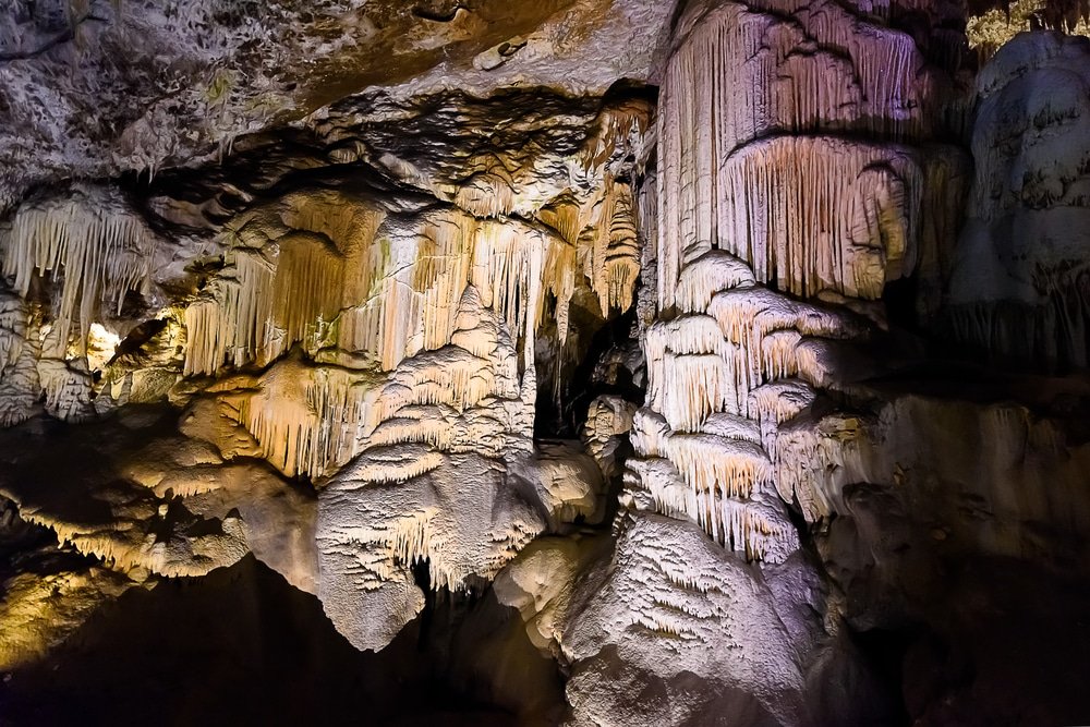 Stalactites and stalagmites inside an illuminated limestone Postojna Cave Park in Slovenia.