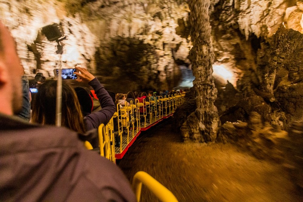 Tourists on a train ride through a scenic cave in Slovenia - Postojna Cave Train