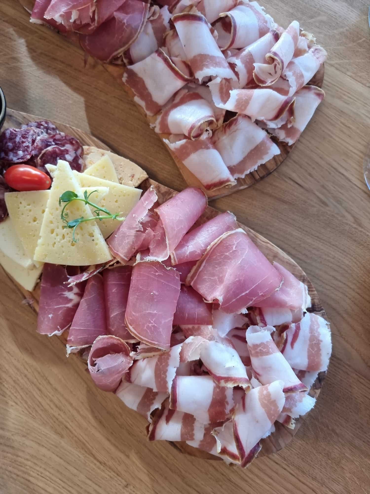 A platter of meat, cheese, and Istrian specialties on a wooden table at Tomaz Winery.