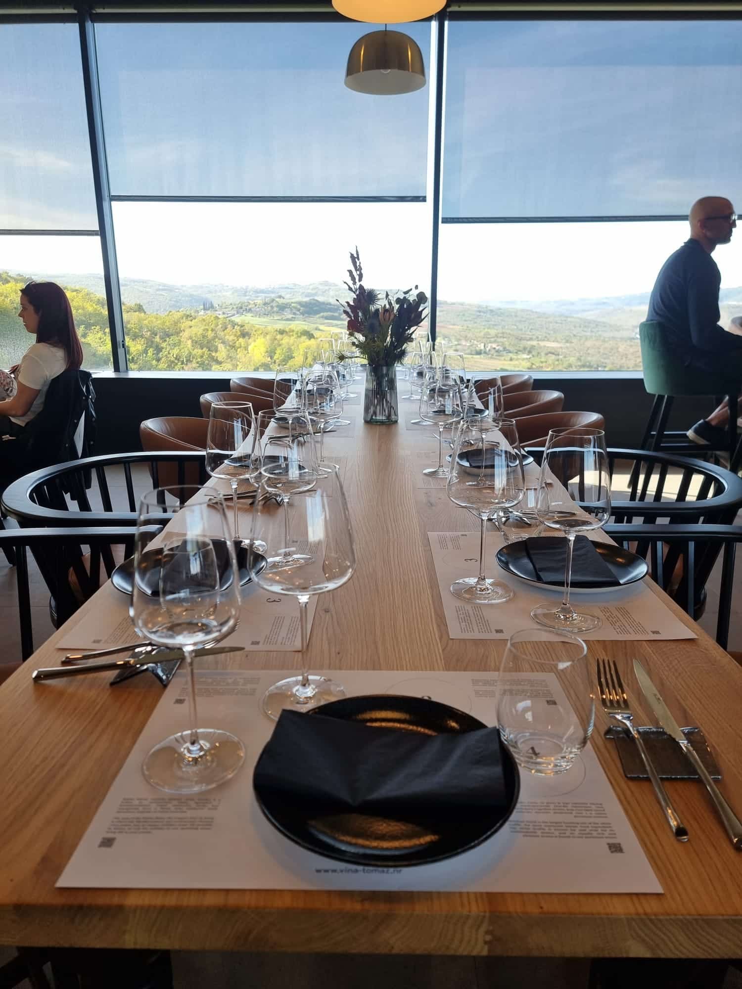 A long table is set up in a restaurant with a view of Istria.