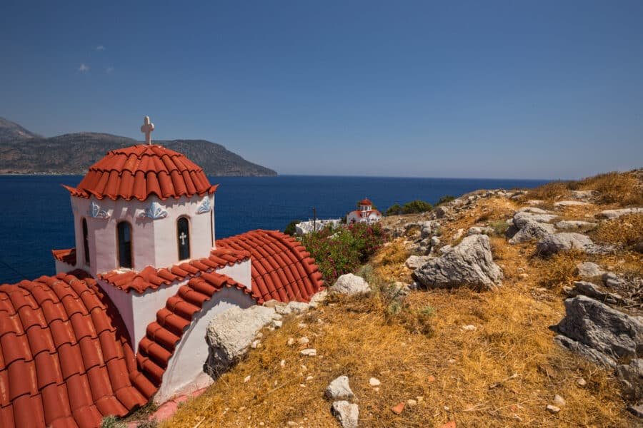 A church on Karpathos Island, Greece, perched atop a cliff and offering stunning panoramic views of the ocean.