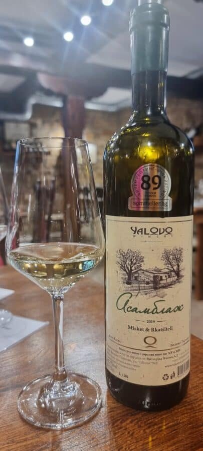A bottle of olive oil next to a glass of wine, perfect for indulging in while enjoying the charming things to do in Veliko Tarnovo.