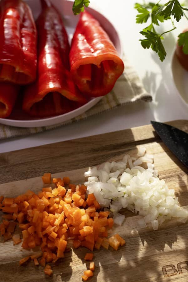 A colorful medley of palneni chushki and onions is beautifully displayed on a cutting board.