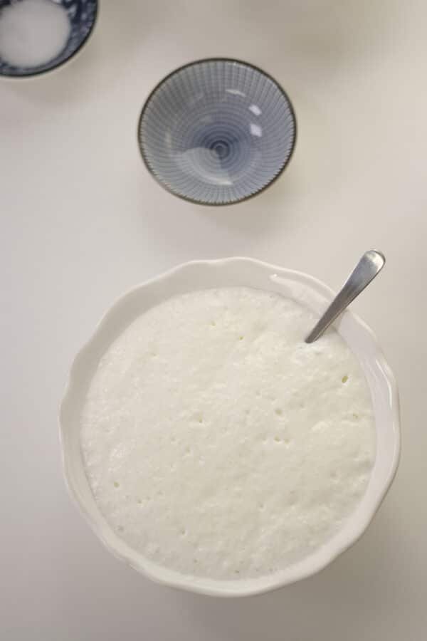 A bowl of rice and a spoon on a white table.