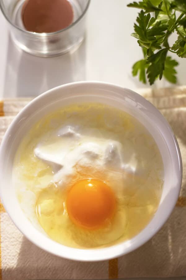 An easy white bowl with an egg in it.