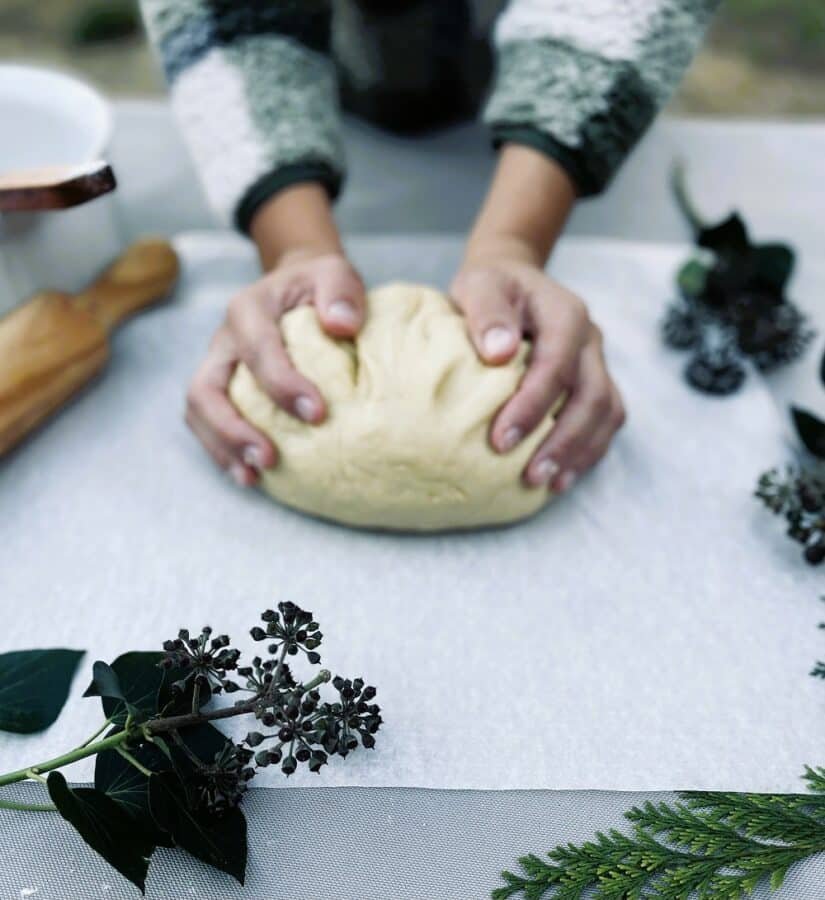 A person is kneading dough on a table to prepare a delicious recipe for homemade Crescent Rolls.