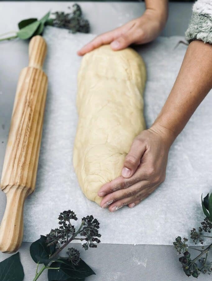 A person rolling out crescent roll dough with a rolling pin.