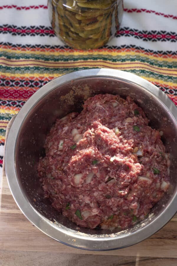 How To Make Bulgarian Meatloaf: A bowl with meat in it next to a pickle.