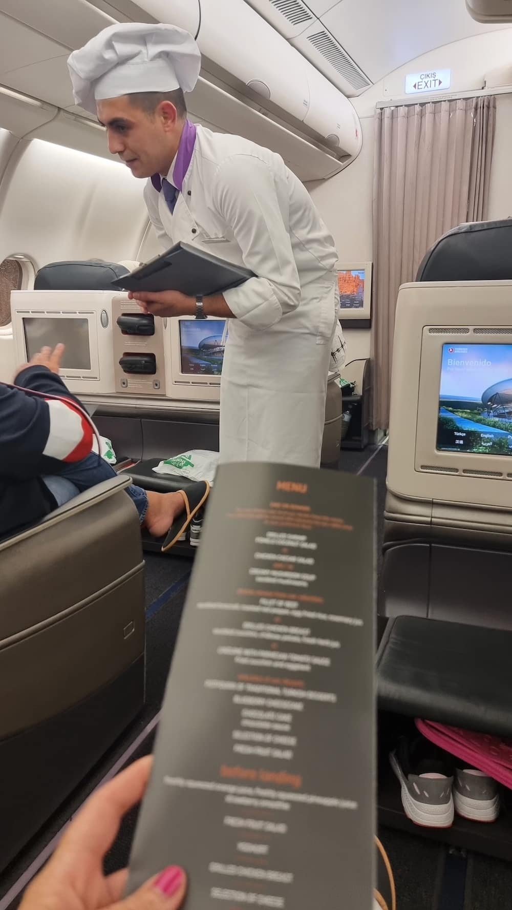 A First Timer on a Turkish Airlines Business Class flight is holding a menu in an airplane.