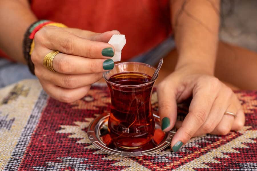 A woman pouring traditional Turkish tea into a cup for breakfast in Turkey
