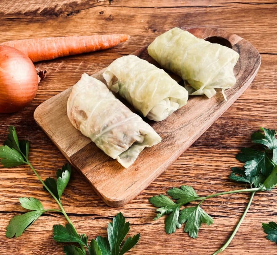 Steps to make sour cabbage rolls with carrots and onions on a wooden cutting board.