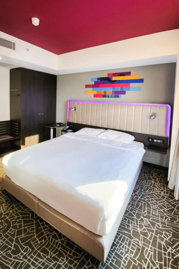 Enjoy your stay in a vibrant hotel room in Izmir with a large bed and a colorful ceiling.