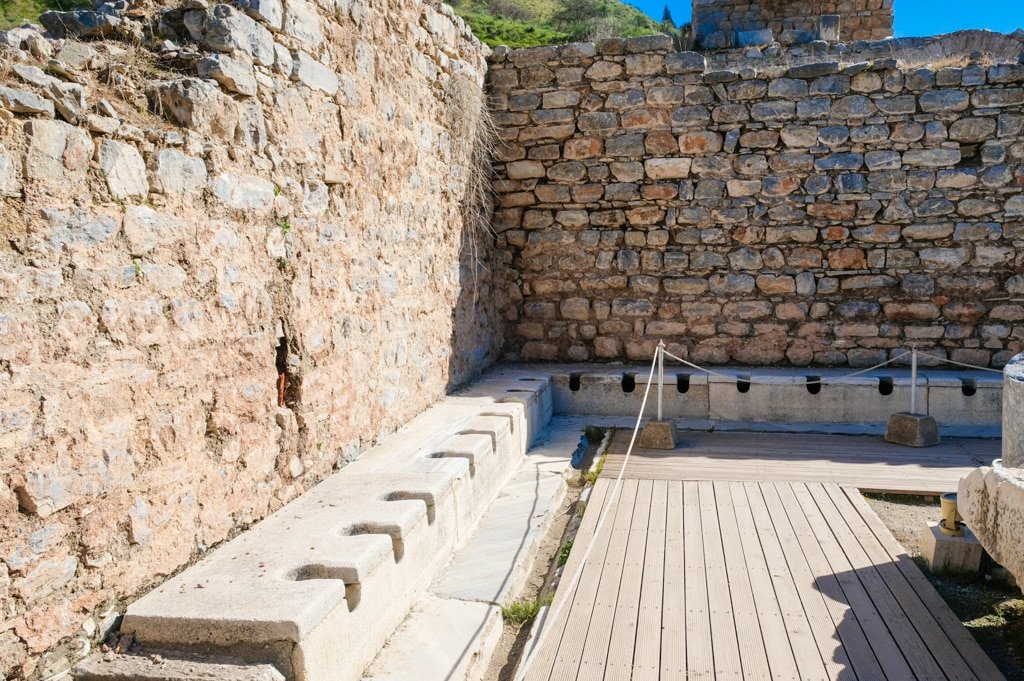 An ancient stone building with a wooden walkway, reminiscent of Ephesus.