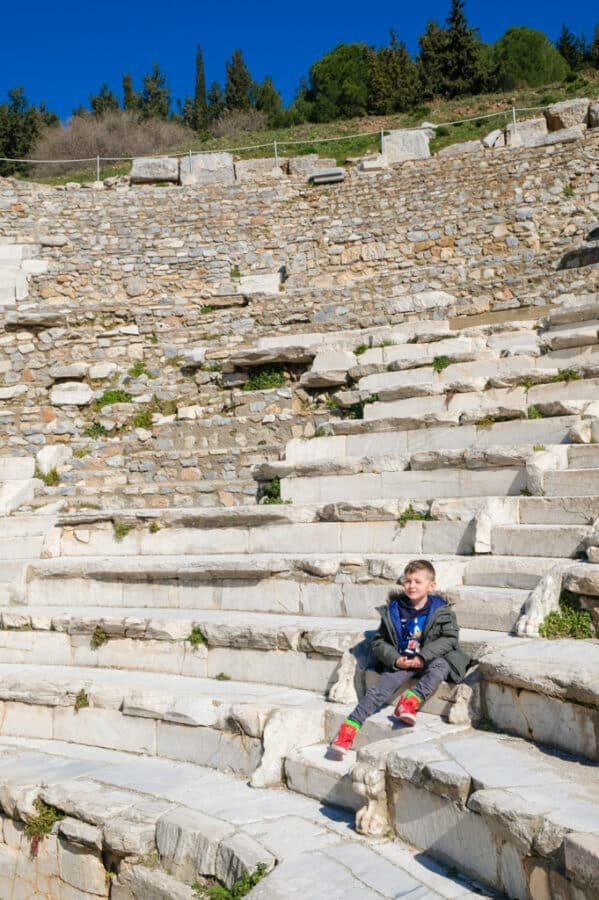 A young boy sitting on the steps of the ancient Ephesus amphitheater.
