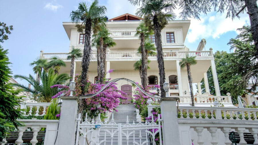 A white house with palm trees and a white gate on the Island of Büyükada, Istanbul - perfect for a day trip.